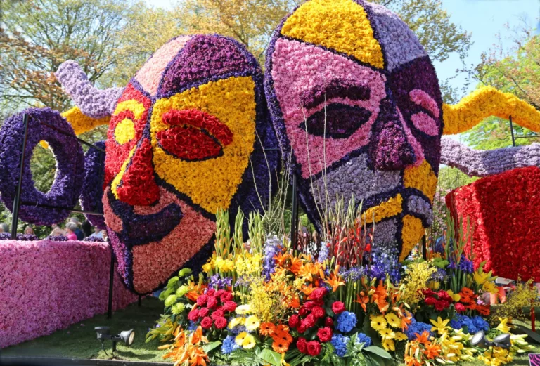 Praalwagen van het Bloemencorso Bollenstreek met twee kleurrijke maskers van hyacinten, tulpen en snijbloemen