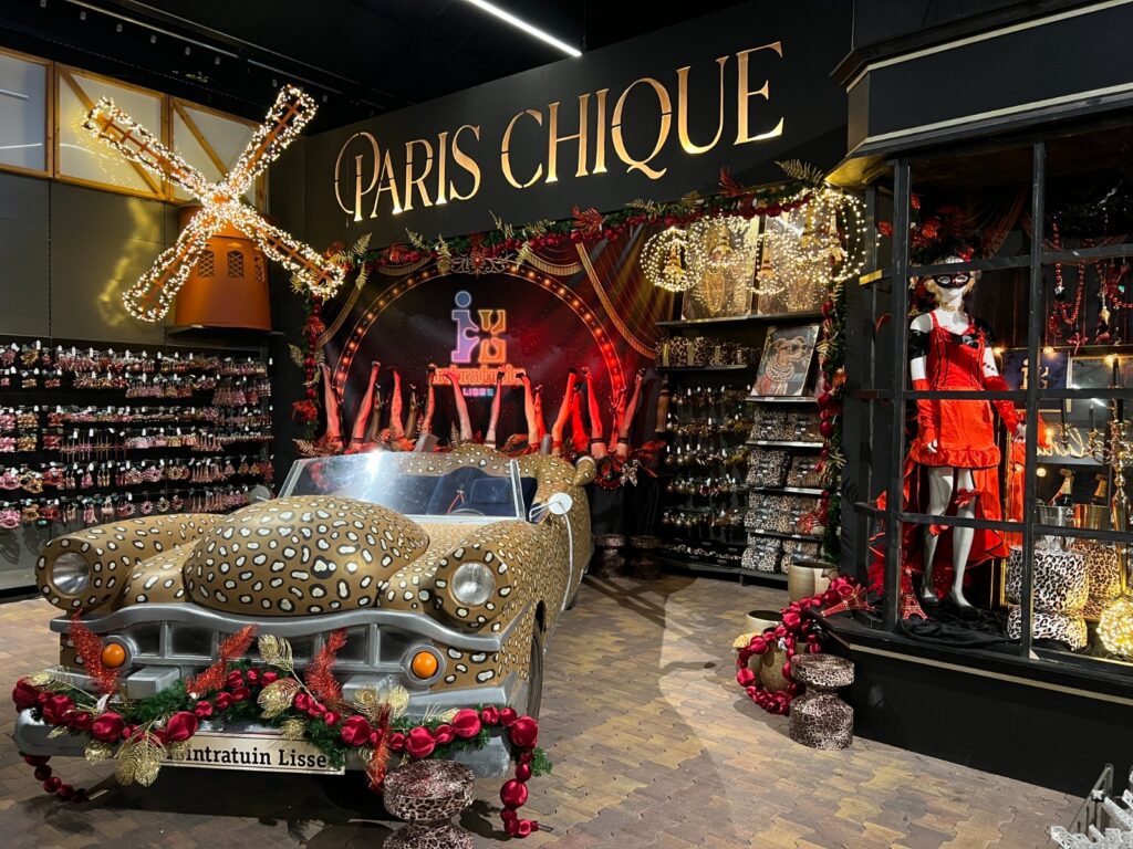 Exposición navideña en Intratuin Lisse con el tema Paris Chique: molino iluminado, coche con estampado de leopardo y decoración navideña en rojo y dorado