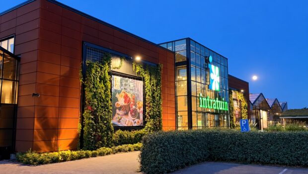 De verlichte ingang van tuincentrum Intratuin Lisse in de avondschemering, met groene gevelbeplanting
